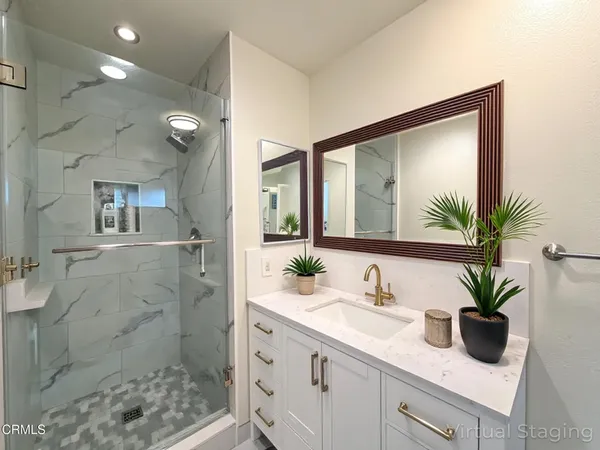 a bathroom with a granite countertop sink a mirror and a shower