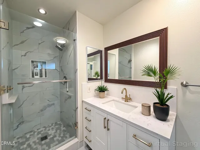 a bathroom with a granite countertop sink a mirror and a shower