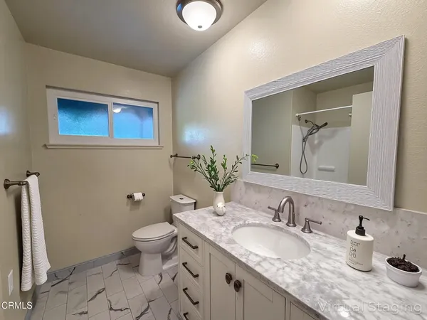 a bathroom with a granite countertop sink mirror and toilet