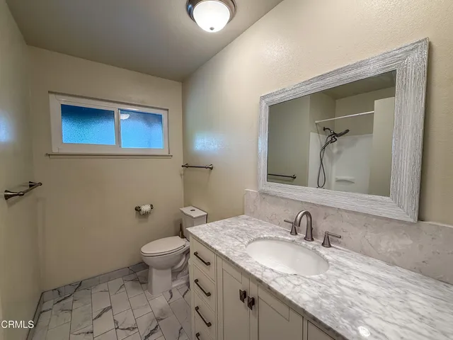 a bathroom with a granite countertop sink mirror and toilet