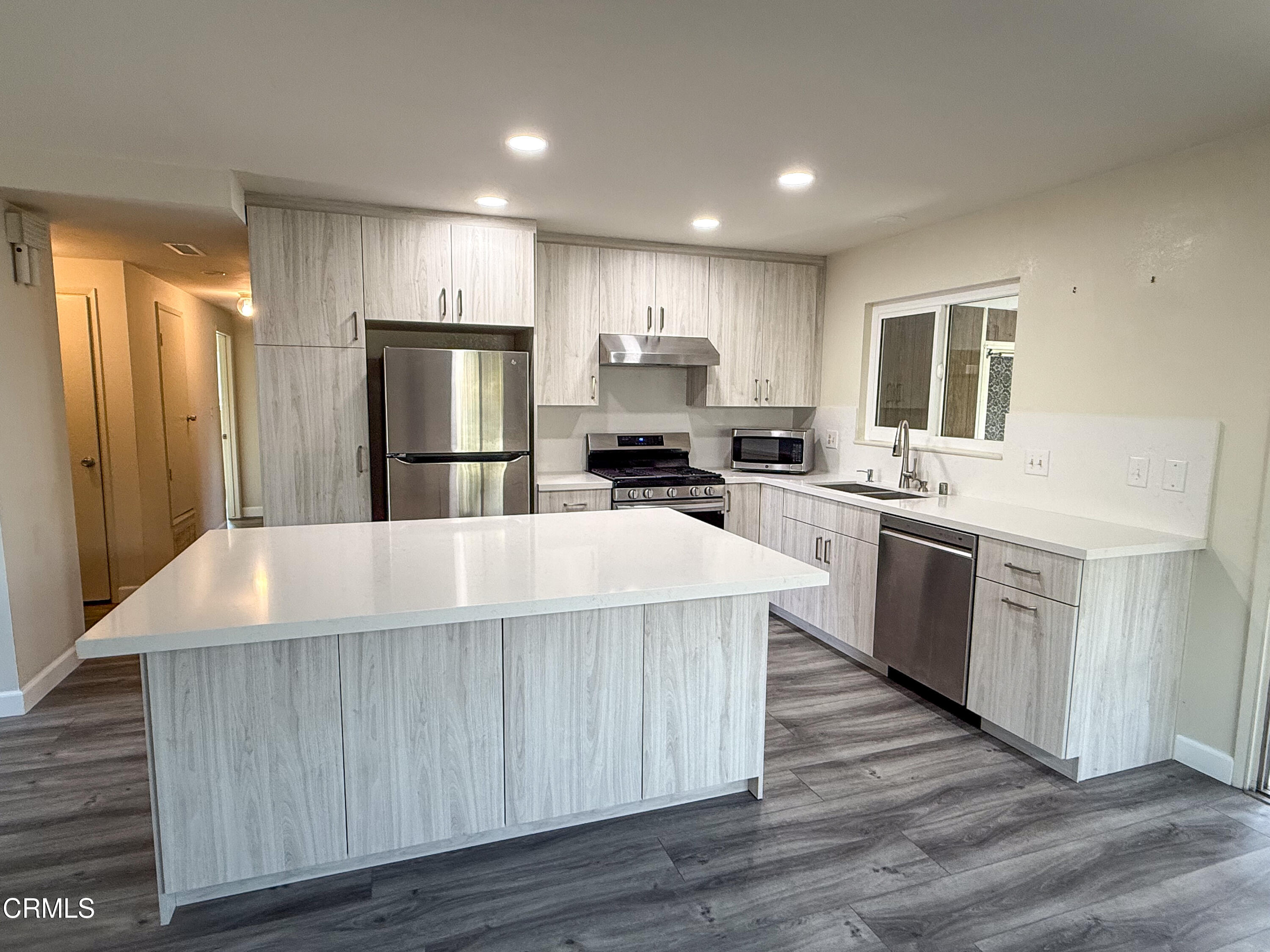 1730 West Hemlock Street Oxnard, CA 93035 - Photo 3 of 25 a kitchen with kitchen island a stove a sink a refrigerator cabinets and wooden floor