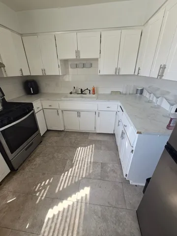 a kitchen with granite countertop a stove a sink and a white cabinets