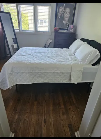 a bedroom with a bed dresser and wooden floor