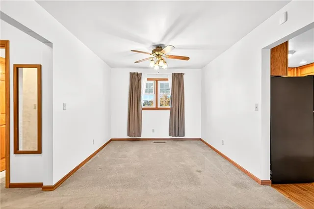 an empty room with windows and chandelier fan