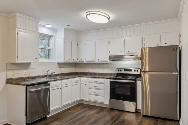 a kitchen with cabinets stainless steel appliances and wooden floor