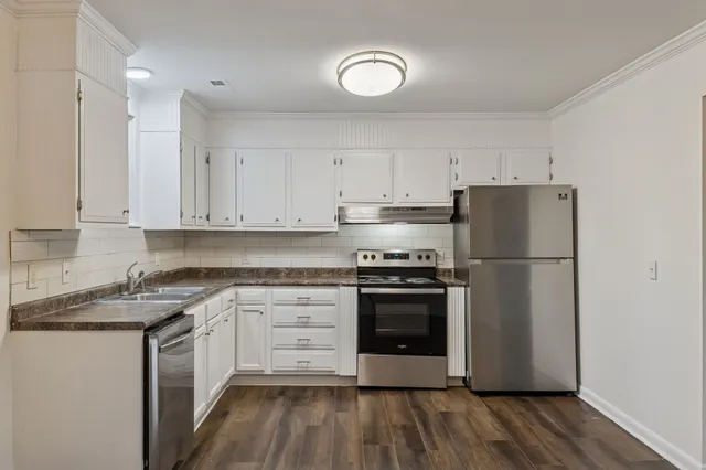 a kitchen with a white cabinets and wooden floor