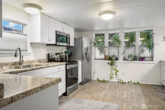 a kitchen with stainless steel appliances granite countertop a sink a stove top oven a counter space and cabinets