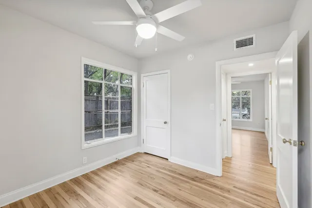 a view of empty room with wooden floor and fan