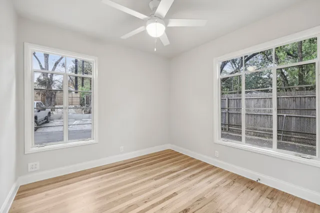 a view of an empty room with a window and wooden floor