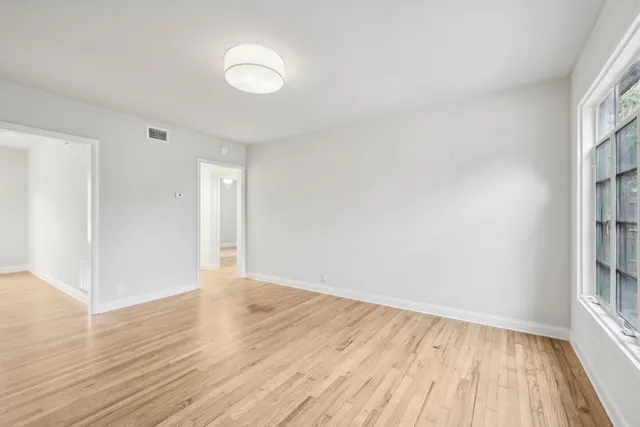 a view of an empty room with wooden floor and a window