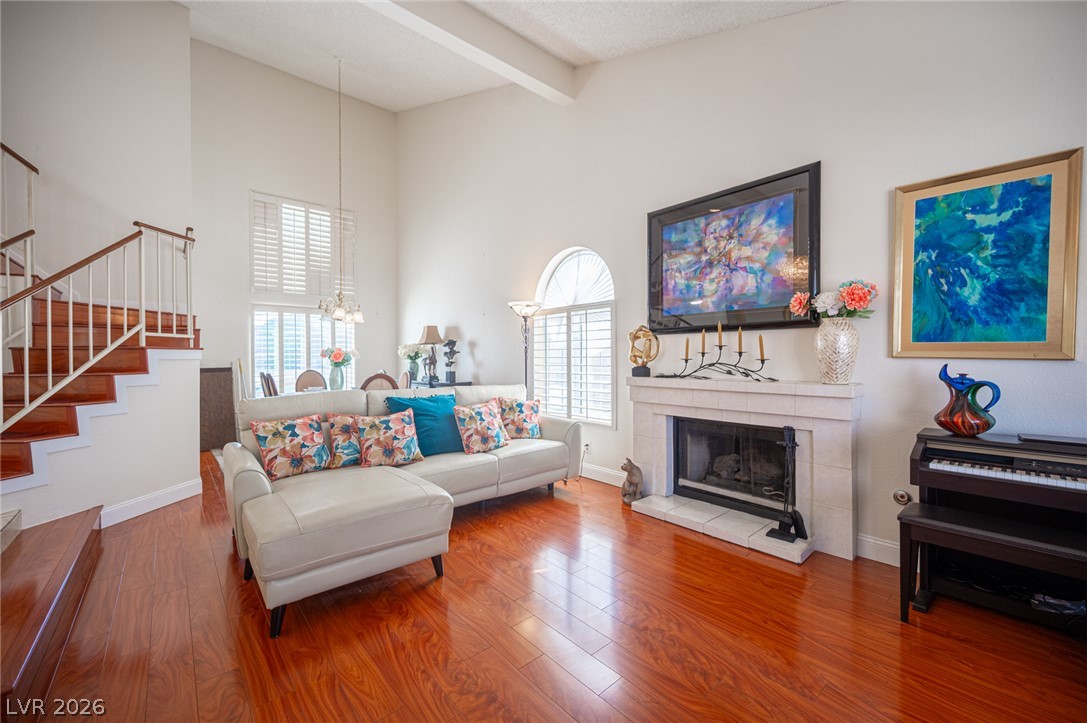 718 Rusty Spur Drive Henderson, NV 89014 - Photo 6 of 50 Rich hardwood flooring leads to a cozy fireplace, framed by soaring ceilings and an elegant staircase.