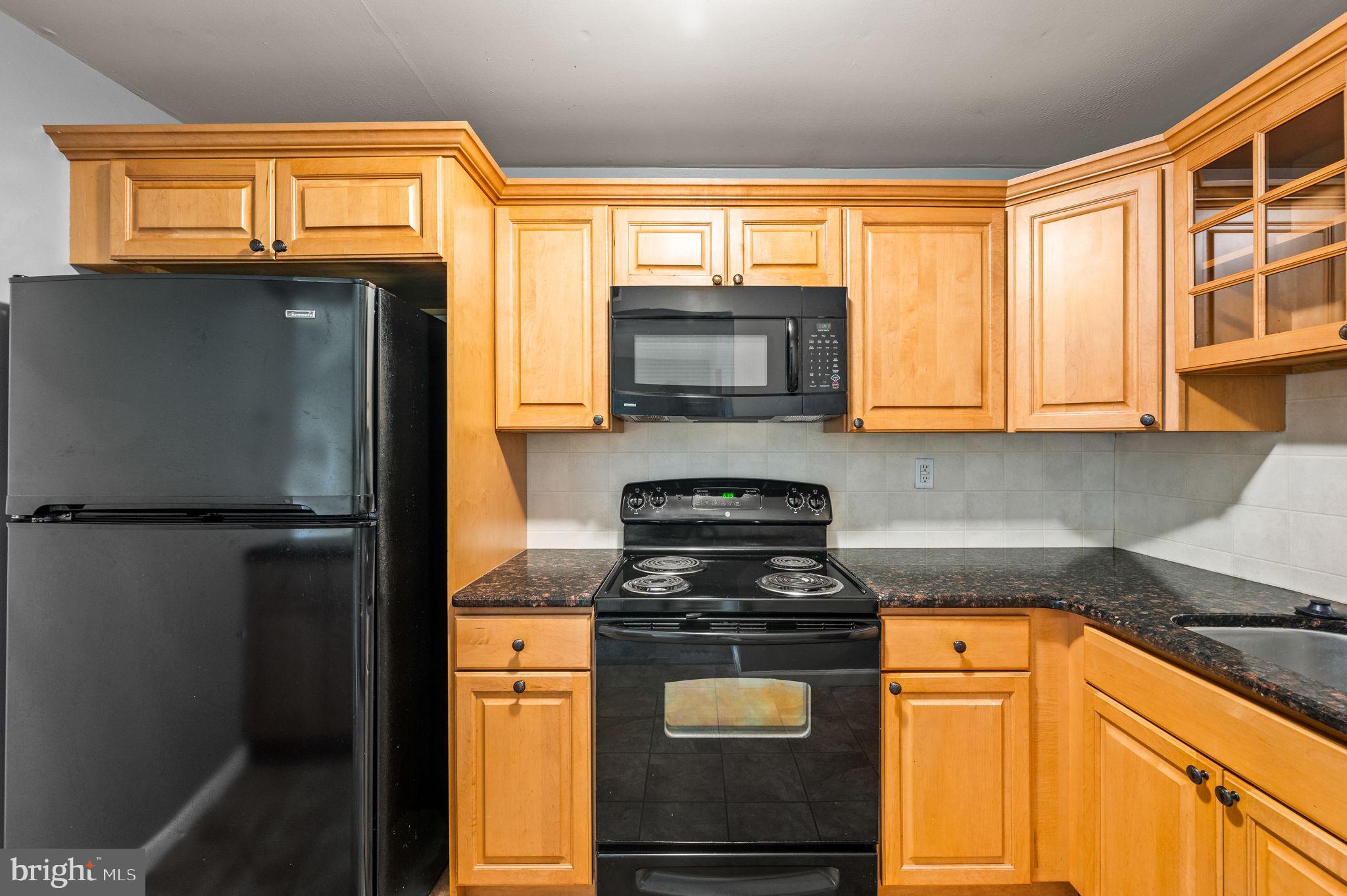 830 Putnam Boulevard, Unit B Wallingford, PA 19086 - Photo 5 of 14 a kitchen with stainless steel appliances granite countertop a refrigerator a stove a sink and a window