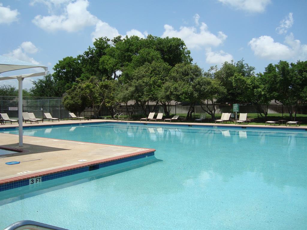 814 Broken Feather Trail Pflugerville, TX 78660 - Photo 21 of 24 A spacious outdoor pool awaits, surrounded by lush trees and ample lounging areas for relaxation.