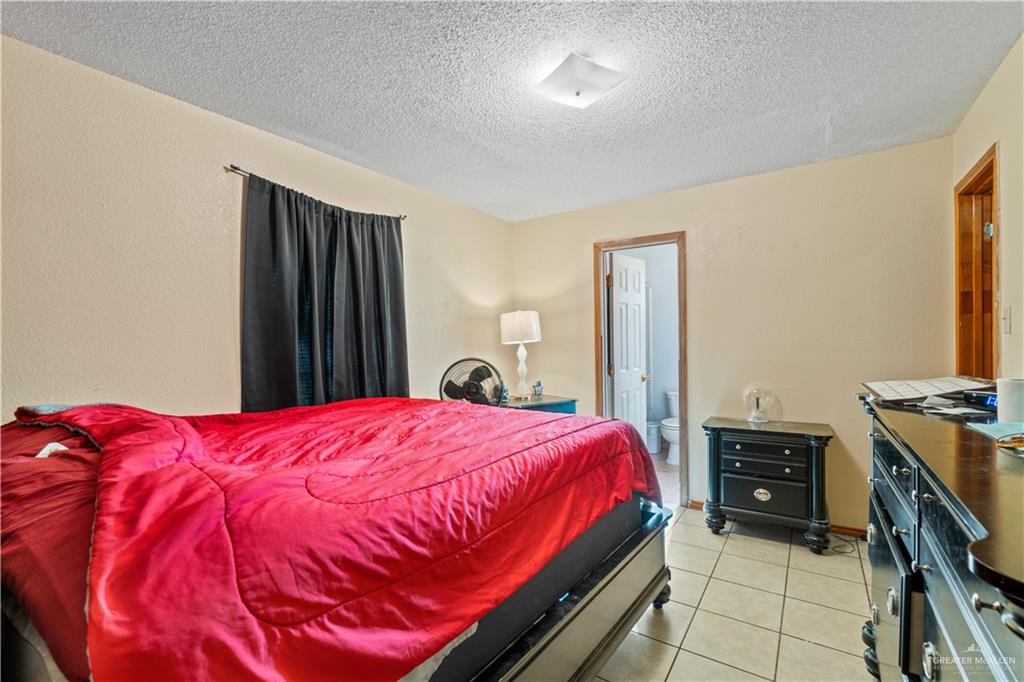 106 Rosa Priego Street Donna, TX 78537 - Photo 12 of 25 Bedroom with light tile patterned flooring, ensuite bath, and a textured ceiling