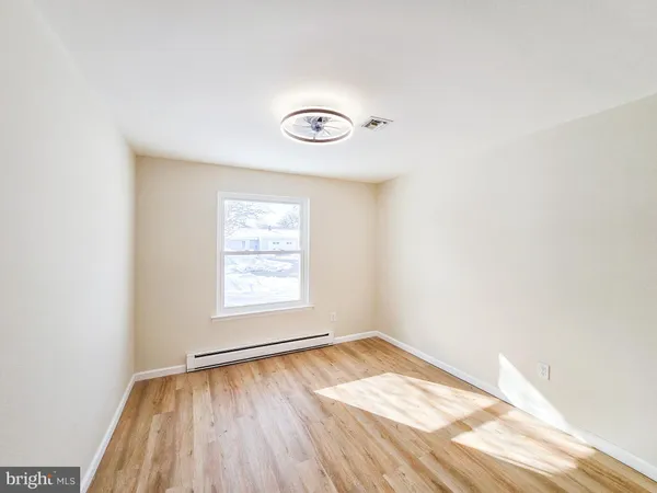 an empty room with a window and wooden floor