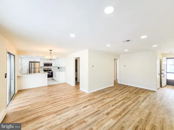 a view of kitchen and empty room with wooden floor