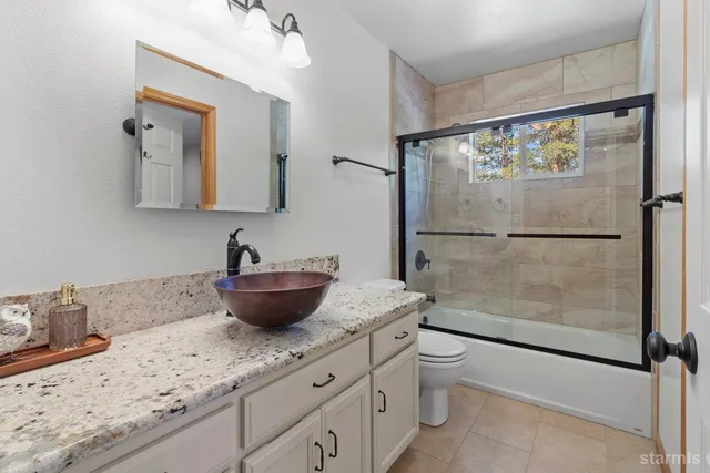 a bathroom with a granite countertop sink a toilet and shower