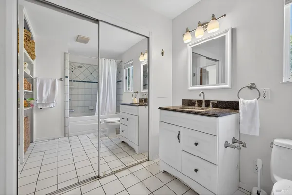 a bathroom with a double vanity sink toilet mirror and shower