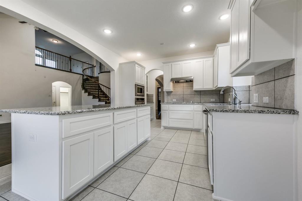 104 Sweetleaf Drive Red Oak, TX 75154 - Photo 14 of 36 Bright kitchen featuring white cabinetry, granite countertops, stainless steel appliances, and a tile backsplash