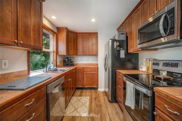 a kitchen with stainless steel appliances granite countertop a stove a sink and a microwave