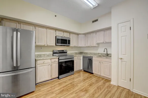 a kitchen with granite countertop a refrigerator stove and sink