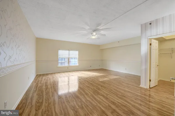 a view of empty room with wooden floor and fan