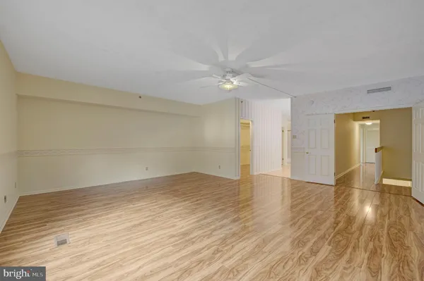 an empty room with wooden floor and ceiling fan