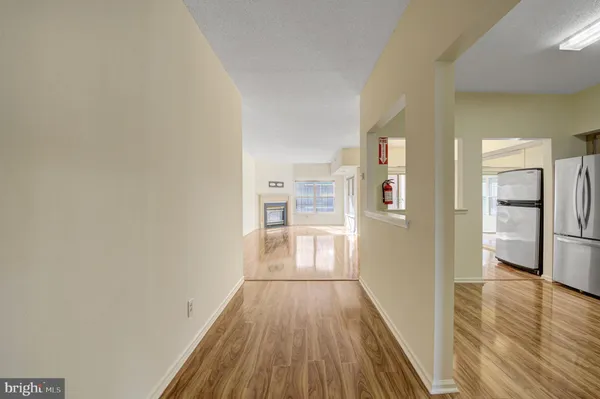 a view of a hallway with wooden floor and a kitchen