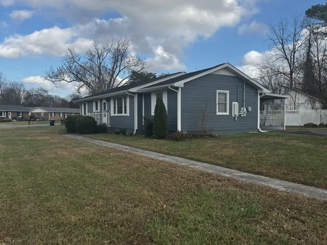 a front view of house with yard and trees in the background