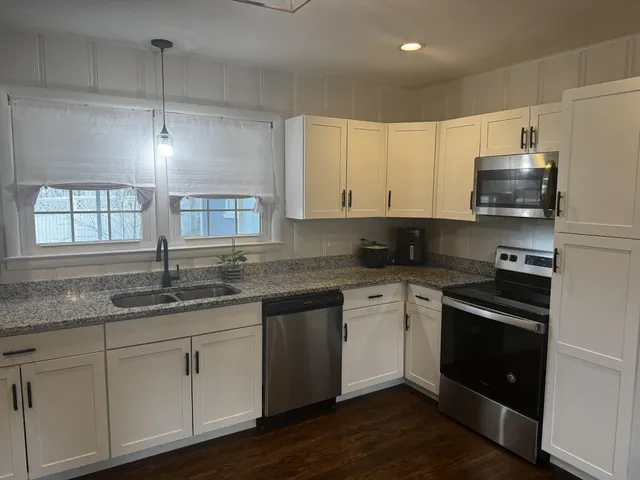 a kitchen with granite countertop white cabinets and a sink