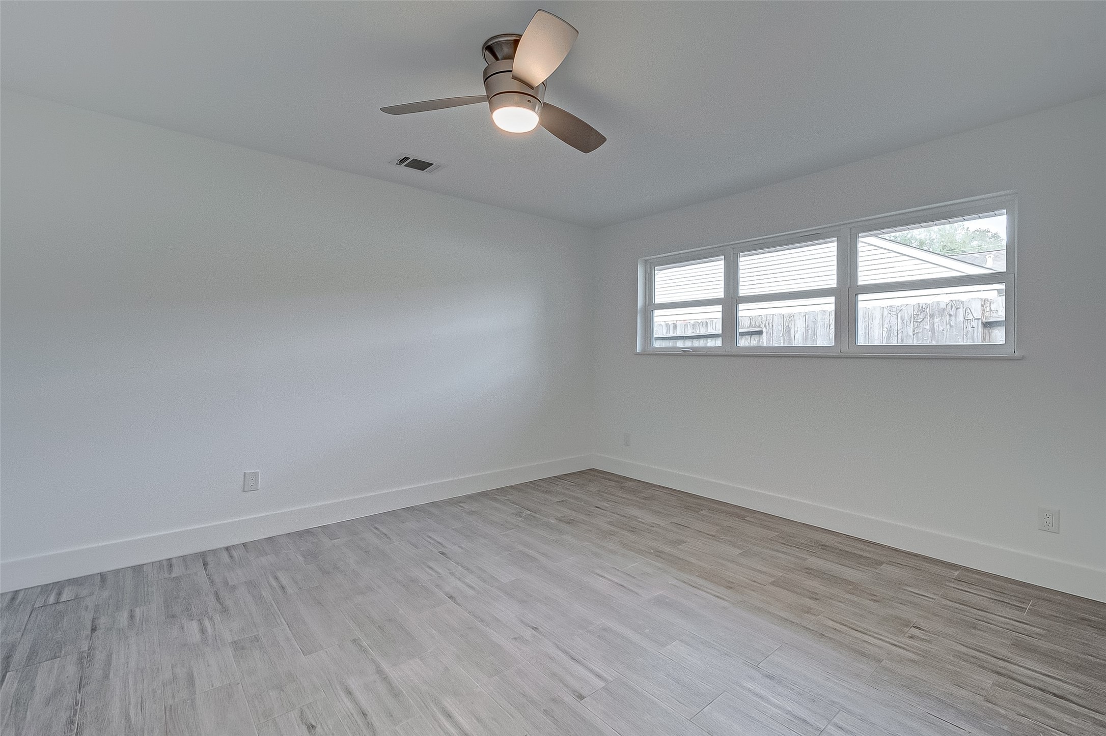5007 Cheena Drive Houston, TX 77096 - Photo 21 of 40 an empty room with wooden floor fan and windows