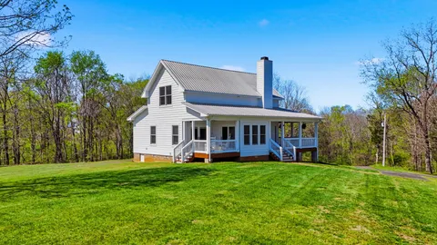 a view of a house with a yard porch and a tree