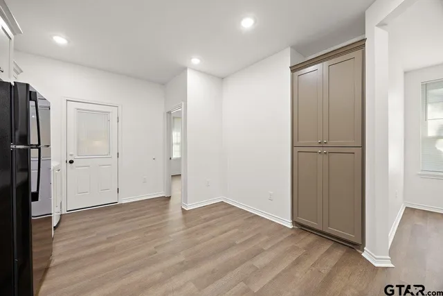 a view of an empty room with wooden floor and a ceiling fan