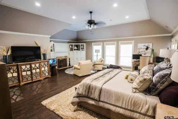a bedroom with bed a flat tv screen and a bookshelf