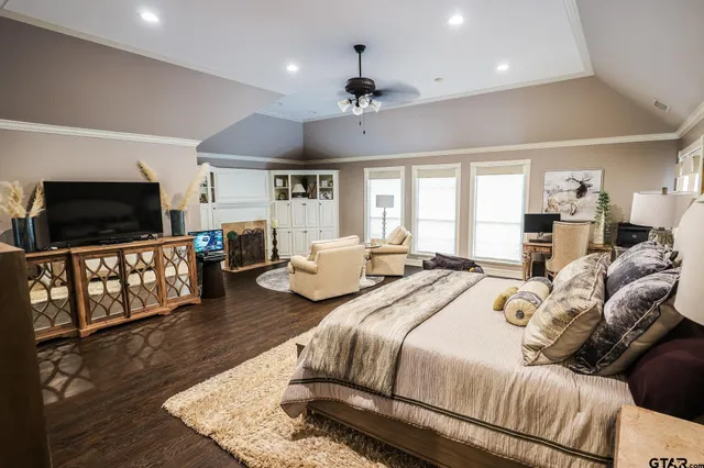 a bedroom with bed a flat tv screen and a bookshelf