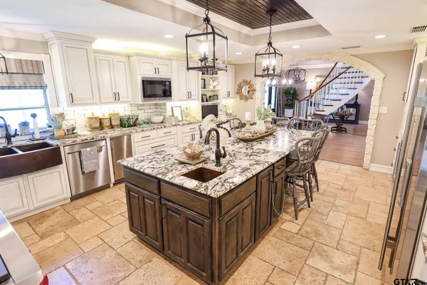 a kitchen with granite countertop a sink a counter top space appliances and cabinets
