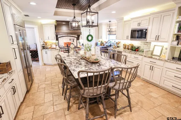 a kitchen with stainless steel appliances kitchen island granite countertop a refrigerator a stove a sink dishwasher and a dining table with wooden floor