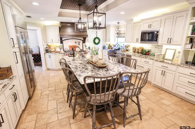 a kitchen with stainless steel appliances kitchen island granite countertop a refrigerator a stove a sink dishwasher and a dining table with wooden floor