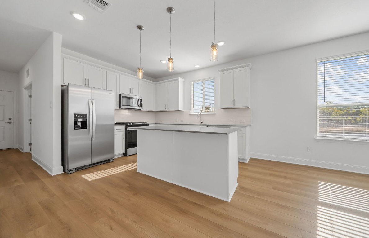 501 Maries Garden Georgetown, TX 78626 - Photo 5 of 24 a kitchen with stainless steel appliances granite countertop a refrigerator a sink dishwasher a stove and white countertops with wooden floor
