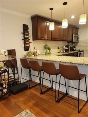 a kitchen with stainless steel appliances granite countertop a stove top oven a sink a dining table and chairs with wooden floor