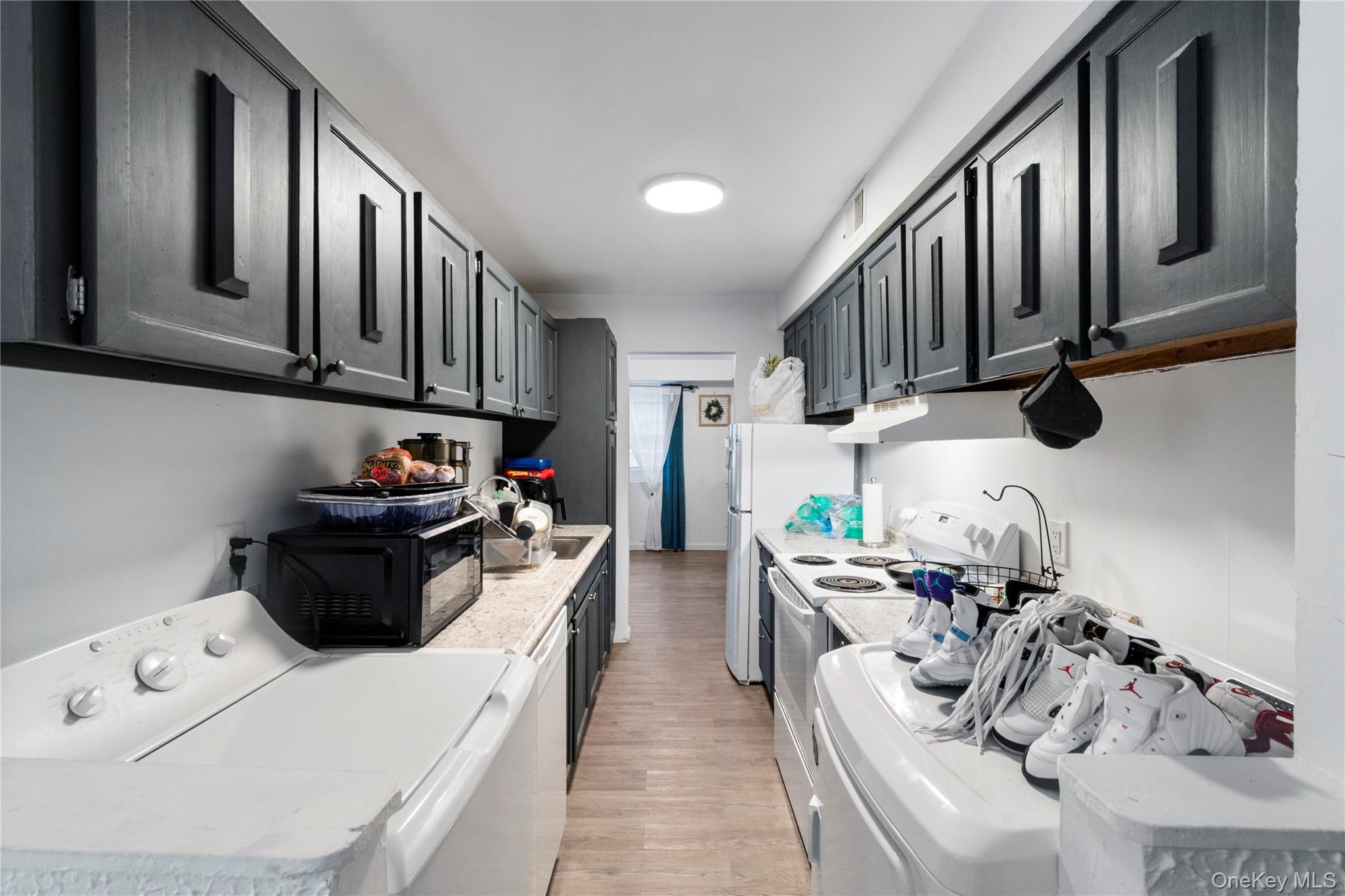 231 Hill Rise Calverton, NY 11933 - Photo 7 of 14 a kitchen with stainless steel appliances a stove a refrigerator white cabinets and couches