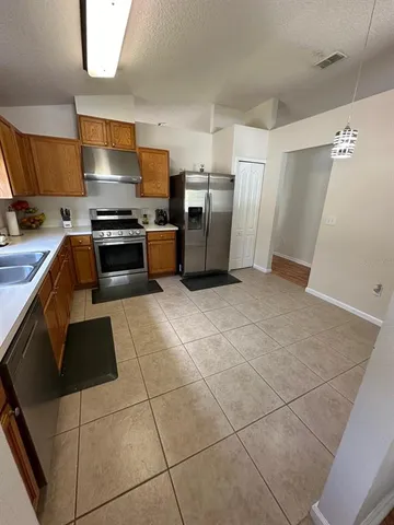 a kitchen with granite countertop a refrigerator and a stove top oven