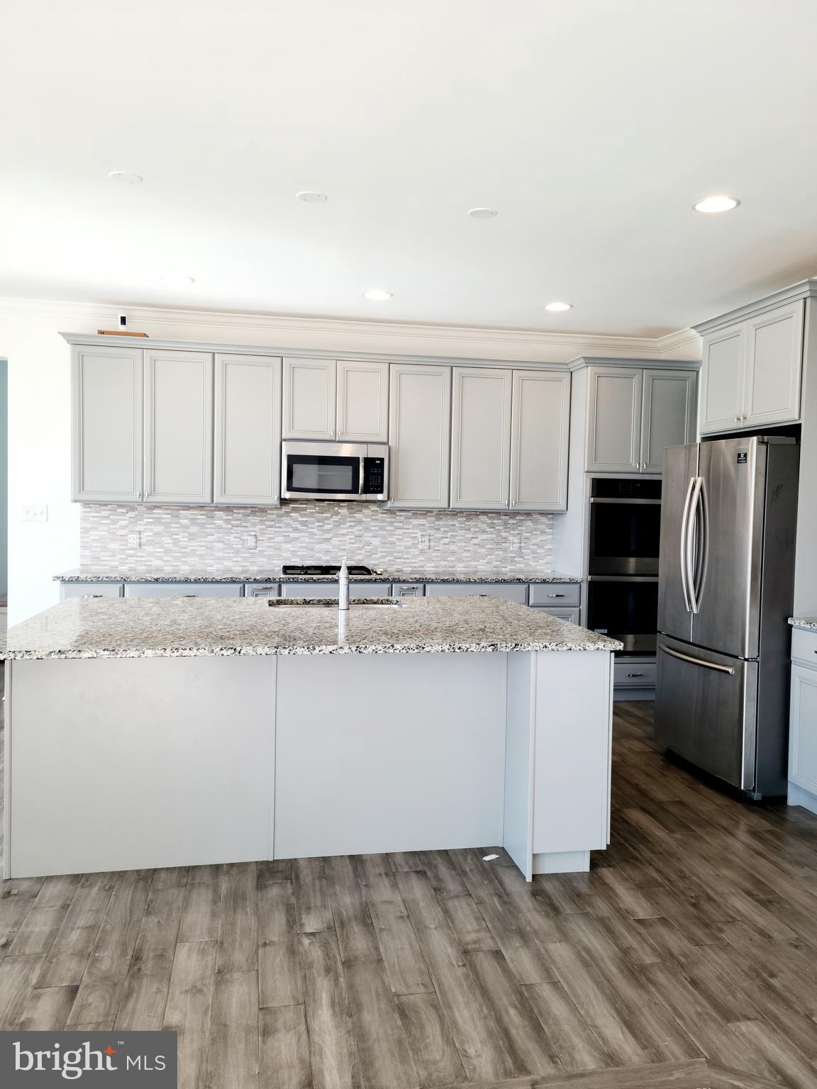 1756 Michelangelo Drive Middletown, DE 19709 - Photo 5 of 24 a kitchen with kitchen island granite countertop white cabinets and stainless steel appliances