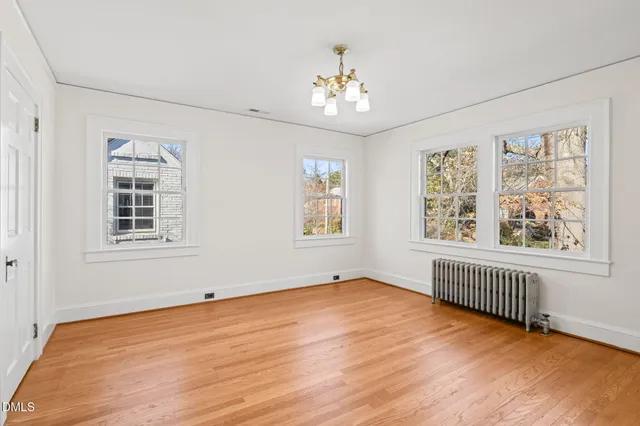 a view of an empty room with a window and wooden floor