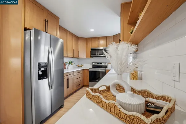 a kitchen with stainless steel appliances granite countertop a refrigerator a sink dishwasher a stove and a refrigerator with wooden floor