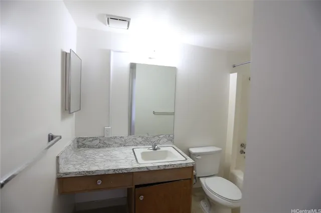 a bathroom with a granite countertop sink toilet and mirror