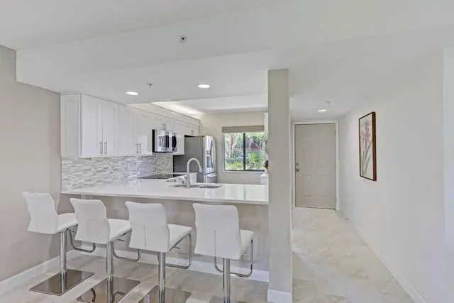 a kitchen with kitchen island granite countertop a dining table chairs cabinets and stainless steel appliances