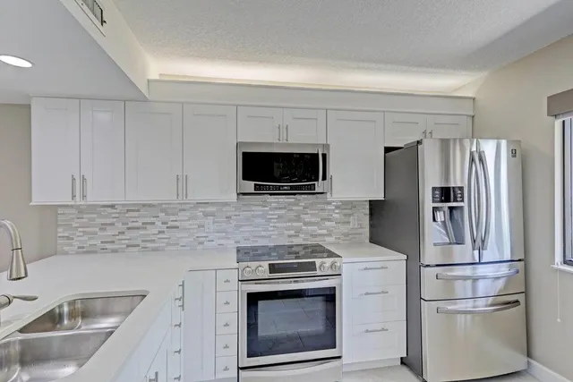 a kitchen with refrigerator a microwave a sink and cabinets