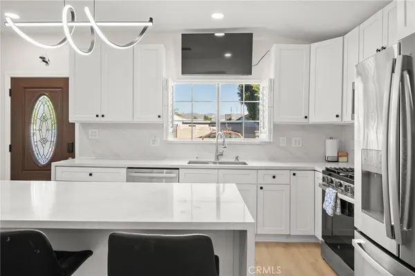 a kitchen with stainless steel appliances kitchen island granite countertop a table chairs sink and cabinets
