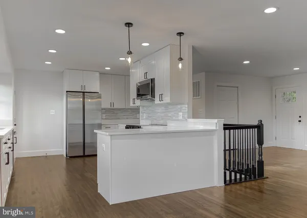 a kitchen with stainless steel appliances a white stove top oven cabinets and a wooden floor